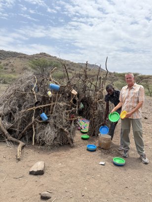 Achim steht mit Joseph (Lehrer) vor der Küche und zeigt die neuen Teller die wir gekauft haben