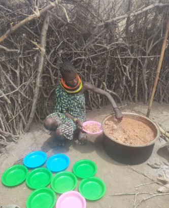 Eine der Köchinnen befüllt die Teller mit dem Brei aus Mais und Bohnen
