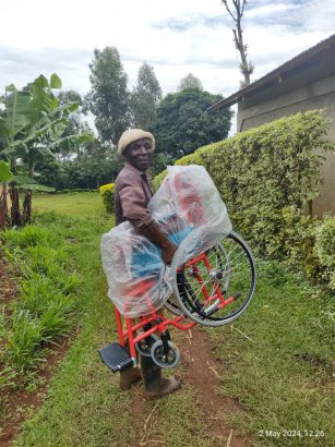 Papa trägt stolz und dankbar den nagelneuen Rollstuhl zum Haus